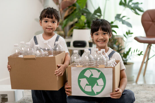 Smiling children having fun while segregating plastic bottles and paper into a bin