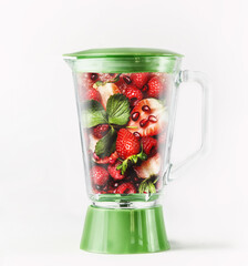 Blender with red fruits: strawberries, raspberries, mint leaves and pomegranate seeds. Refreshing...