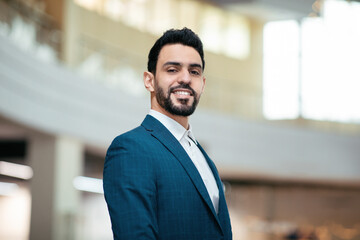 Smiling confident attractive young arab guy, general manager with beard in suit looks at camera