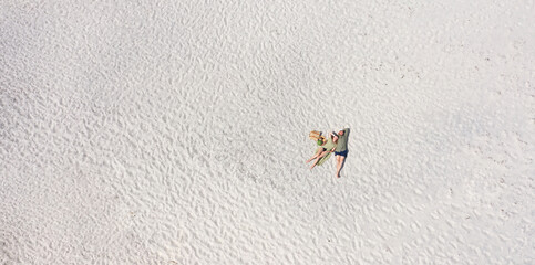 Aerial view of a young couple lying on the white sand. man and woman spend time together and travel through the desert