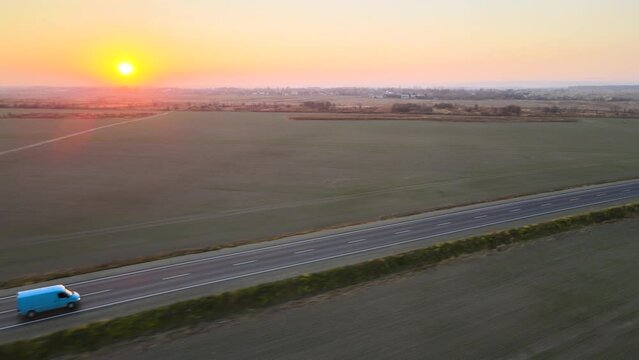 Aerial view of small cargo van driving on highway hauling goods at sunset. Delivery transportation and logistics concept