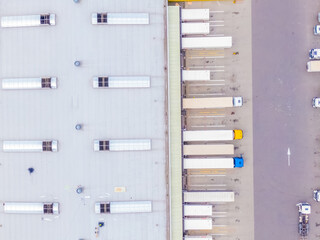 Aerial view of colorful trucks in the terminal waiting for unloading. Top view of the logistics center. Transportation. Freight transport, delivery. International road transport.