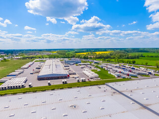 Aerial view of goods warehouse. Logistics center in industrial city zone from above. Aerial view of trucks loading at logistic center