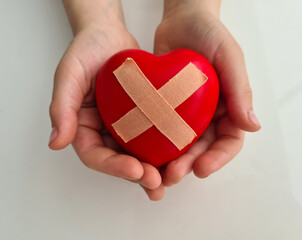 Wounded heart with band-aid in children hands