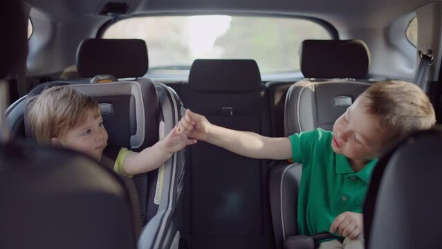 Cute toddler boy and preschool girl sitting in car seat. Child transportation safety, family travel. High quality 4k footage