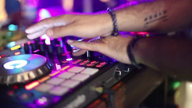 close-up of DJ working at bar pressing buttons moving sliders at party 