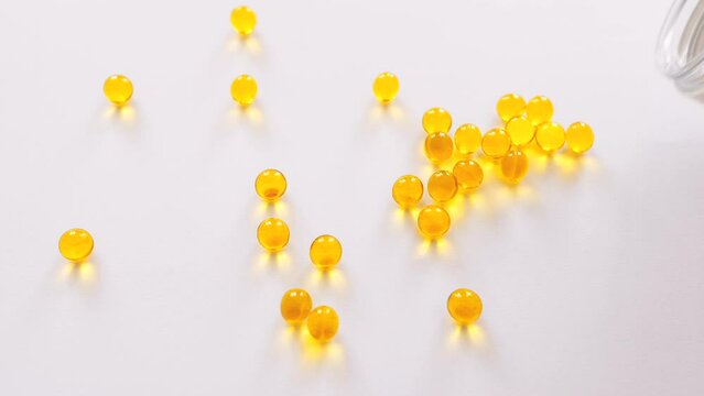 Vitamin D, A, E or omega 3 fish oil in the yellow pill concept. Golden capsules on the white background. 