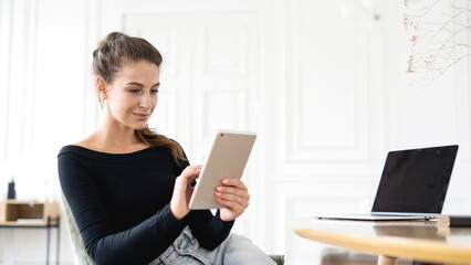 A young woman is smiling working in an office using a device computer