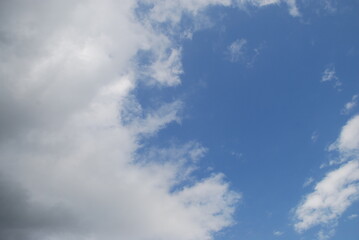 Layered clouds against the sky. Multilevel white clouds are floating in the light blue sky. Clouds of different shapes and sizes are illuminated by the sun and they are fluffy in appearance.