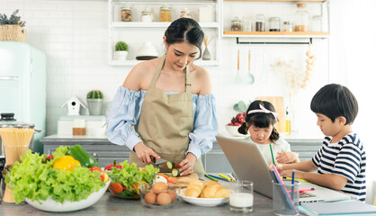 Asian young single mother making food while taking care child in kitchen. home school and single...
