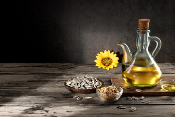 Sunflower oil and sunflower seeds on dark rustic background with shadows and copy space.