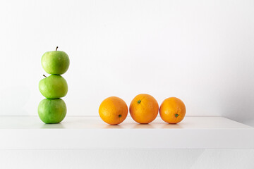 Green apples and oranges on a white background close-up.