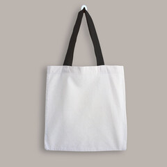White blank cotton eco tote bag with black straps, design mockup. Shopping bag hanging on wall - 504740377