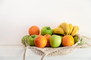 White string bag with fruits on a white background.