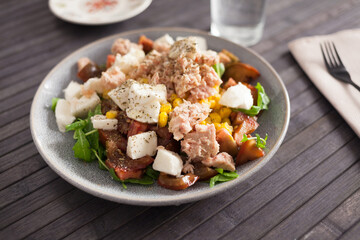 Fish salad with canned tuna and corn, tomatoes and arugula