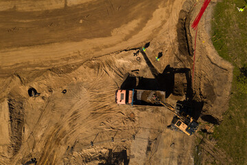 Drone top down view of construction site and excavator excavating soil