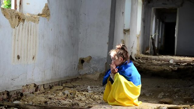 A child in a war-torn house. War in Ukraine. Ukrainian children against the war. A child prays in a bomb shelter. Consequences of the bombing of Ukrainian cities. Destruction in Ukraine.