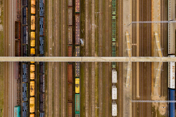 Aerial view of colorful freight trains with goods and bridge on the railway station.
