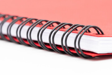 Close up of spirall notebook with red cover on white background