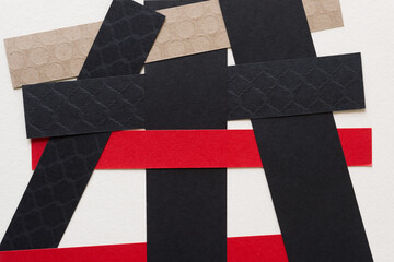 overlapping paper stripes (mostly in black, red, and brown)