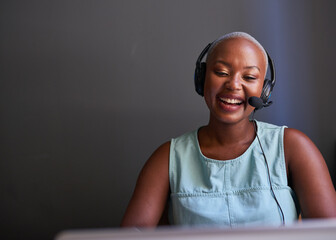 A young Black call centre agent laughs while on a call with headset