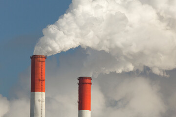 White puffs of smoke from the chimneys of a thermal power plant. Central heating in winter. Environmental pollution. Close-up view.
