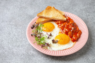 Continental breakfast - eggs, micro greens and beans in tomato sauce on a plate on the table. Healthy breakfast