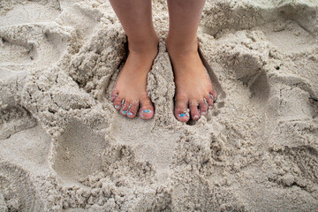 young girl's feet on a summer sandy beach