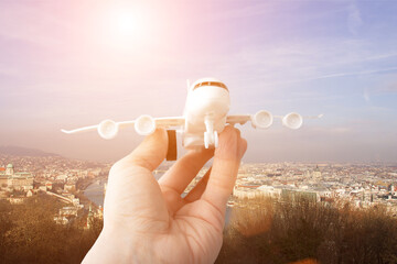 travel,tourism and vacation,holidays,air travel insurance,air tickets online booking, hand with a toy airplane on the background of budapest hungary