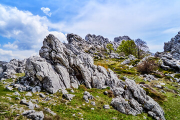 Rock formation of light limestone under blue-white sky in Velebit mountains in Dalmatia, Croatia
