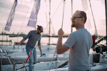 Preparation for the regatta at the yachting school at the marina with sailing yachts. - obrazy, fototapety, plakaty