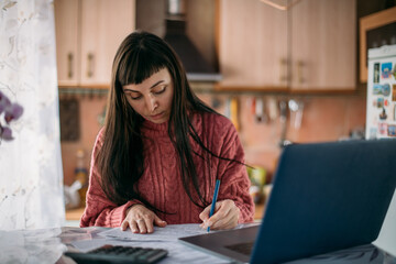 A young woman sorts out utility bills, makes a calculation of expenses for the month. The concept...