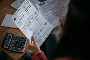 Close-up of female hands with pay slips, utility bills, account statements, payment receipts. A...