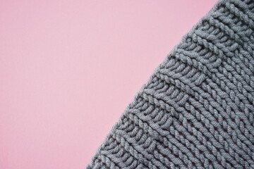 Cozy gray knitted sweater on pink table, copy space