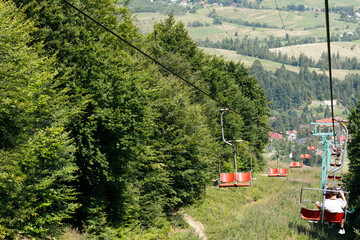 Ski elevator with red chairs moving down. Carpathians Gimba Mountain. 