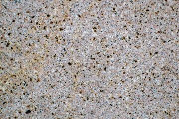 Granular area composed of pink, black and rusty spots.