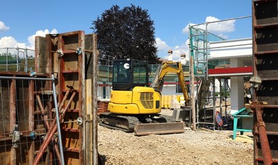 Fototapeta na wymiar Mini excavator at work in a new development area, among eco friendly houses under construction.