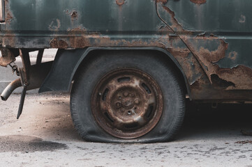The flat tire of a rusty abandoned car