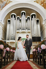 A wedding photo shoot in the organ hall. Red carpet, bridal bouquet. Beautiful antique stained glass windows