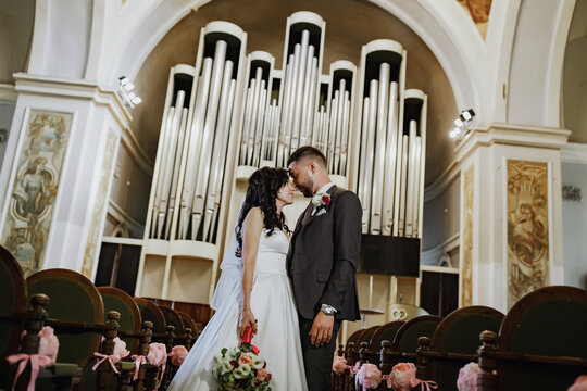 A Wedding Photo Shoot In The Organ Hall. Red Carpet, Bridal Bouquet. Beautiful Antique Stained Glass Windows