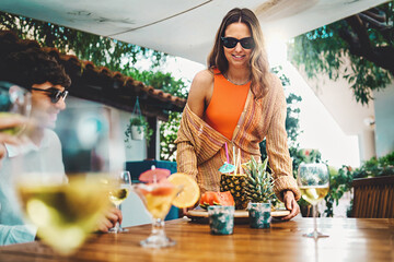 CheerfulYoung woman serves a tray with fruit and fresh soft and healthy drinks to brunch with...