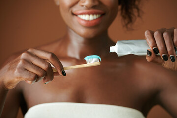 Close-up image of smiling young woman squeezing whitening toothpaste on brush