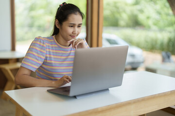 Self Employed, Business Owner, Portrait of an Asian woman using a computer working online or shopping online through the Internet at home