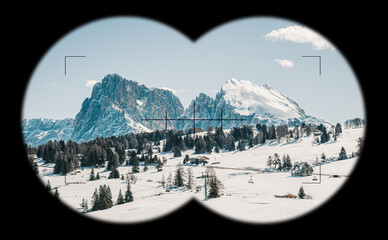 Blick auf die Seiser Alm in Südtirol in einer verschneiten Landschaft mit blauem Himmel in den Bergen, Alpen durch Fernglas,