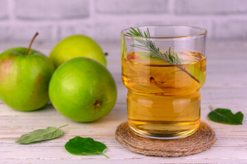 Fototapeta na wymiar A glass of fresh apple juice garnished with a rosemary branch. 