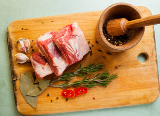 Raw pork ribs, garlic, pepper, bay leaf, on a wooden background. Raw pork rib chops on cut board...