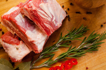 Raw pork ribs, garlic, pepper, bay leaf, on a wooden background. Raw pork rib chops on cut board...
