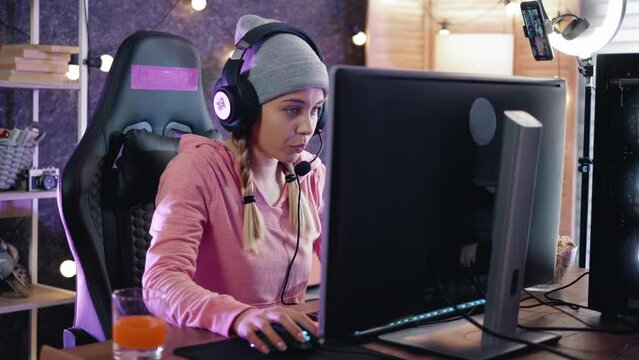 Excited streamer in her room playing online video games with friends online. Female teenager is looking forward to winning by playing an online video game at home