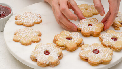 Flower shaped shortbread cookies filled with raspberry jam recipe. Fresh baked cookies close up on marble tray