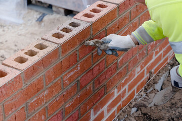 Bricklayer filling joints in the brick wall. Pointing joints in the brick wall - obrazy, fototapety, plakaty